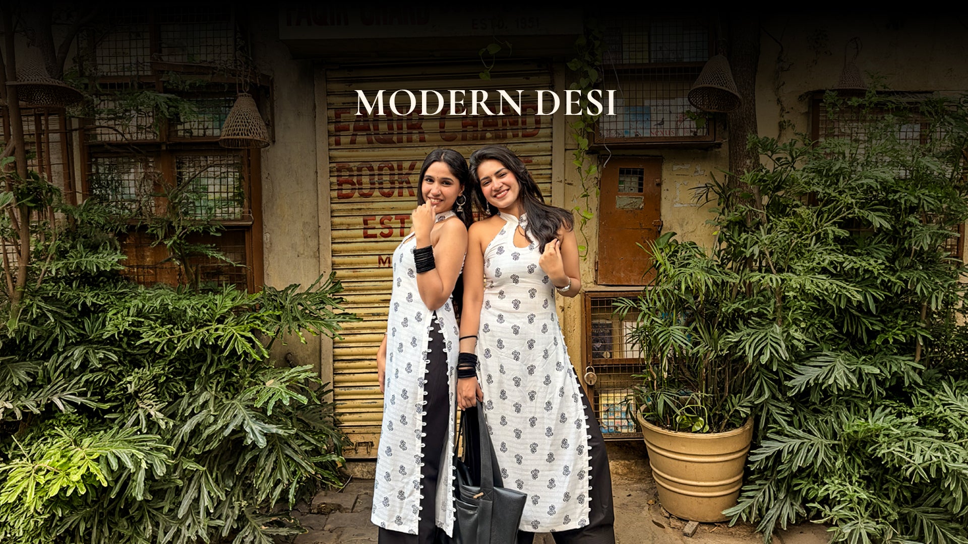 Two women standing together with plants and a store in the background, featuring the brand 'Modern Desi'.