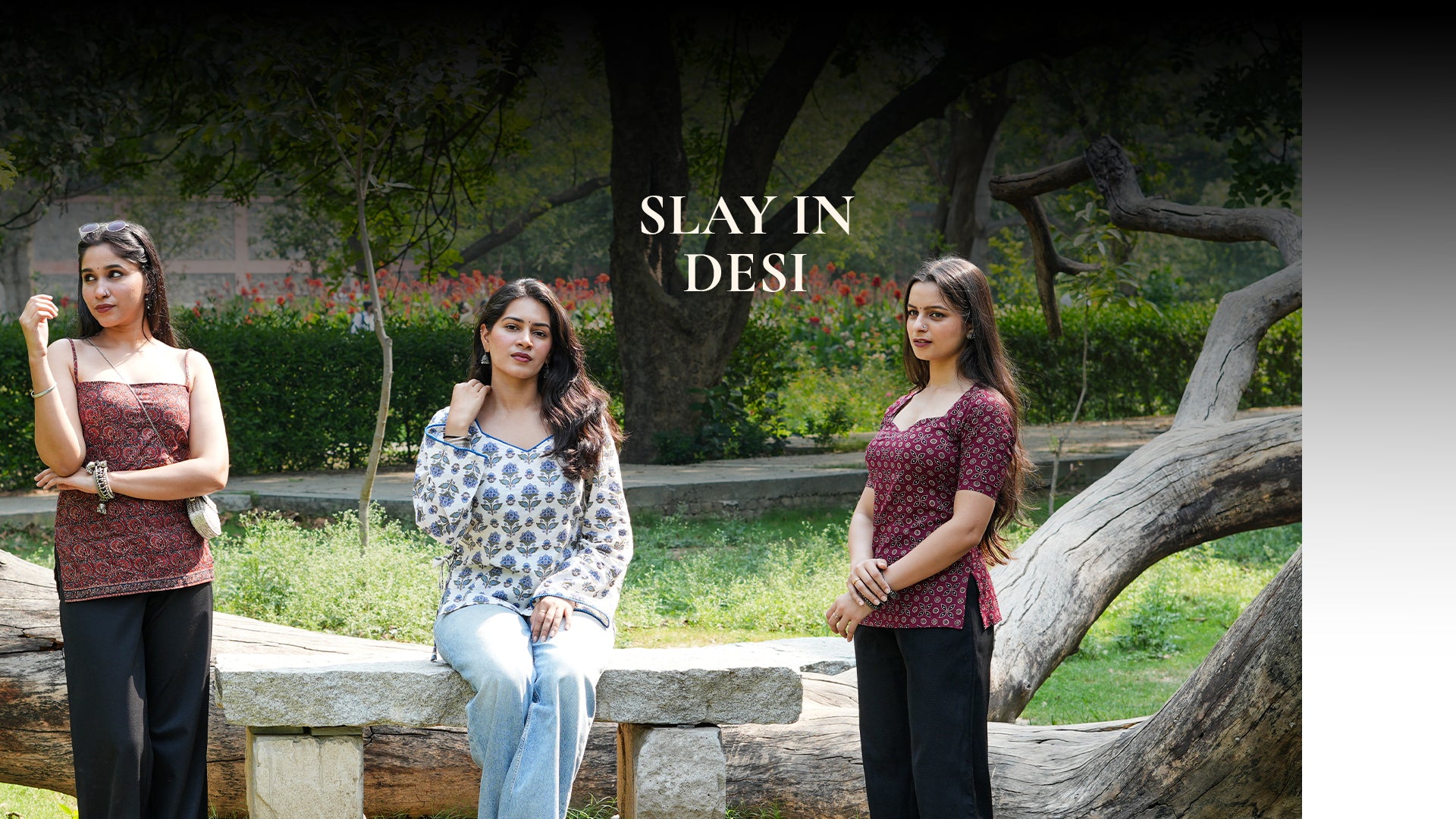 Two women posing outdoors with a tree and bench in the background, featuring the text 'Slay in Desi'.
